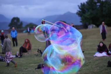20 Haziran 2023 'te İngiltere' deki Castlerigg Taş Çemberi Yaz Gündönümü Kutlaması sırasında dev kabarcıklar çıkaran bir katılımcı ağırlıyor.