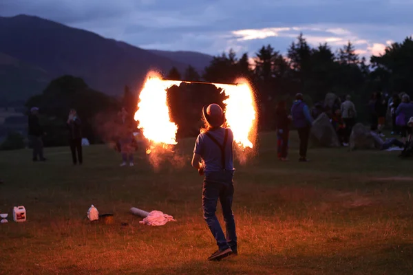 参加者はCastlerigg Stone Circleの間に見物人を楽しませるので火の棒を旋回させます イギリスの夏至祭2023年6月20日 — ストック写真