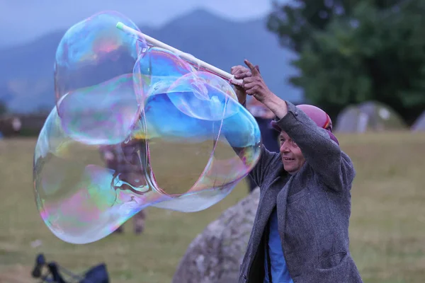 20 Haziran 2023 'te İngiltere' deki Castlerigg Taş Çemberi Yaz Gündönümü Kutlaması sırasında dev kabarcıklar çıkaran bir katılımcı ağırlıyor.