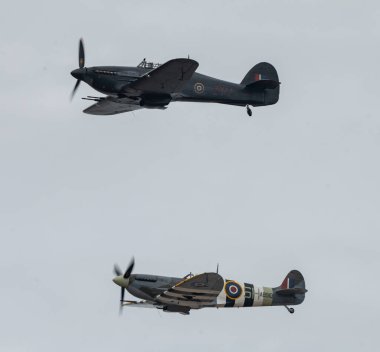 Britanya Muharebesi Hawker Kasırgası PZ865 (yukarıda) ve Mk Vb Spitfire, AB910 (aşağıda) uçuşları, Rhyl Hava Gösterisi 2023 'te Rhyl Seafront, Rhyl, Birleşik Krallık, 27 Ağustos 2023' te gerçekleşmiştir.