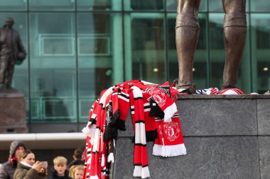 Birleşik eşarplar merhum Sir Bobby Charlton anısına heykelin ayağının dibine konuldu. 23 Ekim 2023 'te Old Trafford, Manchester, İngiltere' nin dışında.