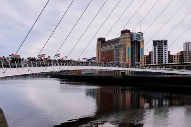 Filistin bayrağı ve pankartlarını taşıyan bir protestocu Filistin yürüyüşü sırasında Newcastle Quayside, Newcastle Upon Tyne, İngiltere, 18 Kasım 2023