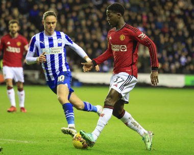 Manchester United takımından Kobbie Mainoo, 8 Ocak 202 'de Wigan, İngiltere' deki Wigan Stadyumu 'nda oynanan ve Wigan FA Cup' ta oynanan üçüncü tur karşılaşmasında Wigan Atletizm takımından Thelo Aasgaard 'ı geçmeye çalışıyor.