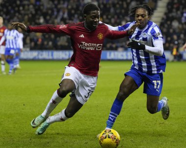 Wigan Atletizm takımından Martial Godo, 8 Ocak 2024 'te Wigan, İngiltere' deki Wigan Stadyumu 'nda oynanan üçüncü tur Dünya Kupası karşılaşmasında Manchester United takımından Kobbie Mainoo ile birlikte top için yarışıyor.