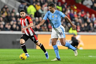 Manchester City 'den Rodri, Premier League karşılaşmasında Brentford' lu Neal Maupay 'ın 5 Şubat 202' de Londra 'daki Gtech Community Stadyumu' nda Manchester City 'ye karşı oynadığı Premier League maçında attığı baskının ardından topu bırakıyor.