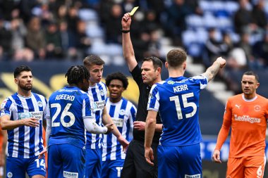 Hakem James Linington, Wigan Athleticli Baba Adeeko 'ya Wigan Atletizm Ligi 1 maçı sırasında DW Stadyumu, Wigan, İngiltere' de Blackpool maçında sarı kart verdi.