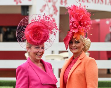 Aintree Yarış Pisti, Liverpool, Birleşik Krallık, 13 Nisan 202 tarihli Randox Ulusal Günü 'nde pembe ve turuncu elbiseli ve şapkalı iki bayan geldi.