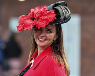 Kırmızı elbiseli ve büyük kırmızı çiçekli siyah şapkalı bir yarışçı, 13 Nisan 202 'de İngiltere' nin Liverpool kentindeki Aintree Yarış Pistine 2024 'teki Randox Ulusal Günü' nde geldi.