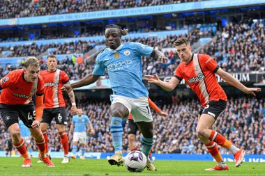 Manchester City 'den Jrmy Doku Premier League maçında Manchester City, Etihad Stadyumu' nda Luton Town 'a karşı, 13 Nisan 2024' te topu oyunda tutuyor.