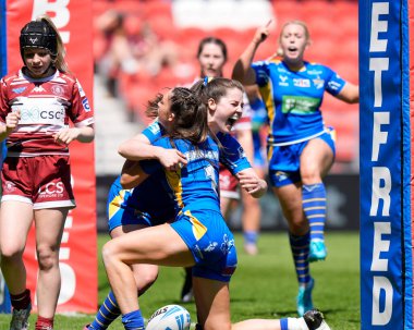 Leeds Rhinos 'tan Izzy Northrop, Leeds Rhinos' tan Ruby Enright ile birlikte 19 Mayıs 2024 'te İngiltere' nin St. Helens Stadyumu 'nda oynanan Betfred Bayanlar Yarışma Kupası Yarı Final karşılaşmasında zaferi kutluyor.
