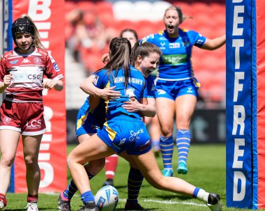 Leeds Rhinos 'tan Izzy Northrop, Leeds Rhinos' tan Ruby Enright ile birlikte 19 Mayıs 2024 'te İngiltere' nin St. Helens Stadyumu 'nda oynanan Betfred Bayanlar Yarışma Kupası Yarı Final karşılaşmasında zaferi kutluyor.