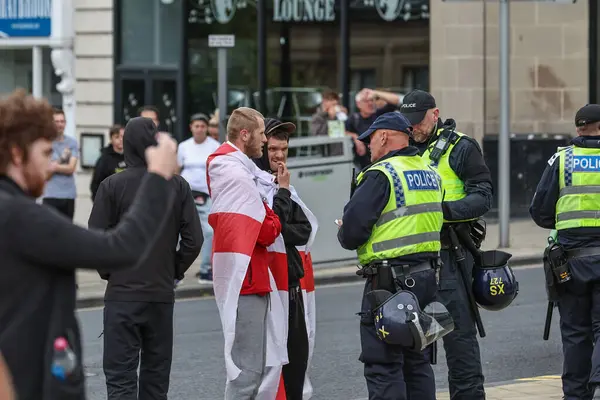 Polis, 8 Ağustos 2024 'te Barnsley, İngiltere' deki ırkçılık karşıtı protesto sırasında gösteri devam ederken kalabalıktaki insanlardan ayrıntıları almaya başladı.