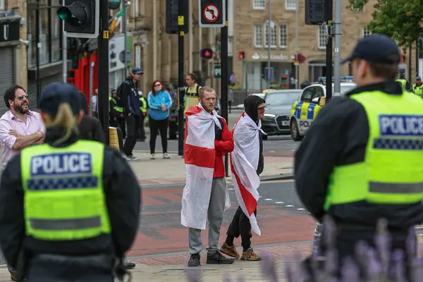 Irkçılık karşıtı protesto sırasında İngiltere bayrağına sarılmış protestocular, Barnsley, Birleşik Krallık, 8 Ağustos 2024