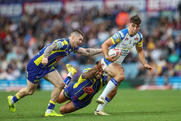 Stock image Jack Sinfield of Leeds Rhinos is tackled by Paul Vaughan of Warrington Wolves during the Magic Weekend match Warrington Wolves vs Leeds Rhinos at Elland Road, Leeds, United Kingdom, 17th August 2024