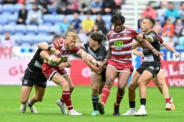 stock image Luke Thompson of Wigan Warriors gets tackled during the Betfred Super League Round 23 match Wigan Warriors vs Hull FC at DW Stadium, Wigan, United Kingdom, 25th August 2024