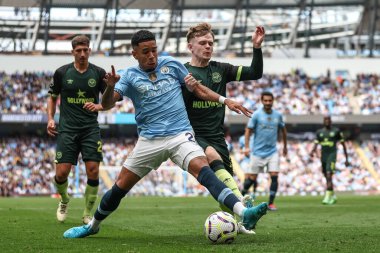 Savinho of Manchester City and Keane Lewis-Potter of Brentford  battle for the ball during the Premier League match Manchester City vs Brentford at Etihad Stadium, Manchester, United Kingdom, 14th September 2024 clipart