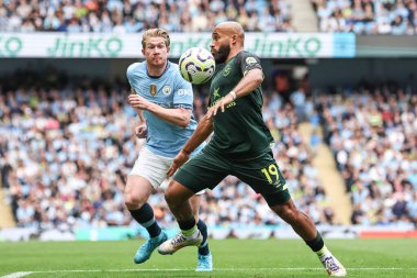 Brentford 'dan Bryan Mbeumo topu kontrol ediyor. Manchester City' den Kevin De Bruyne Premier Lig maçında onu izliyor. Manchester City, Etihad Stadyumu 'nda Brentford' a karşı, 14 Eylül 2024
