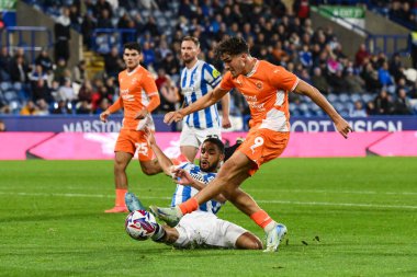 Blackpool 'dan Kyle Joseph kalede şut atıyor ama Huddersfield Town' dan Brodie Spencer 24 Eylül 2024 'te John Smith Stadyumu' nda Huddersfield Town 'a karşı Blackpool' da oynanan Sky Bet 1 maçında topu alıyor.