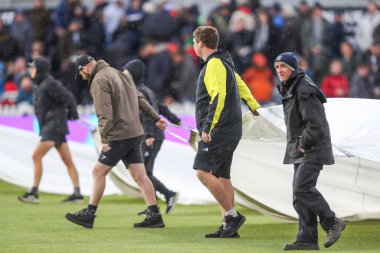 Yer personeli, Birleşik Krallık 'ın Bristol kentindeki Unique Stadyumu' nda oynanan Uluslararası Beşinci Metro Bankası Bir Gün Uluslararası Maçı sırasında yağmurun yağmaya başlamasıyla yağmur örtülerini kaldırıyor.