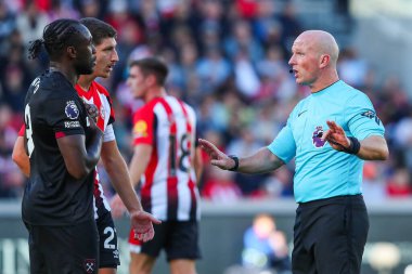 Referee Simon Hooper speaks to the video assistant referee during the Premier League match Brentford vs West Ham United at The Gtech Community Stadium, London, United Kingdom, 28th September 2024 clipart