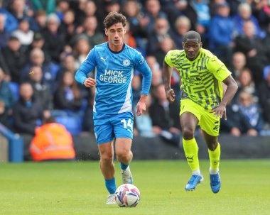 Alex MacDonald topu Rotherham United takımından Christ Tiehi tarafından kovalanırken öne çıkarıyor. Peterborough United - Rotherham United maçı sırasında Weston Homes Stadyumu, Peterborough, İngiltere, 12 Ekim 2024