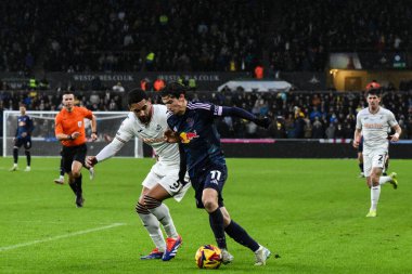 Leeds United takımından Brenden Aaronson 24 Kasım 2024 'te Swansea.com Stadyumu, Swansea.com' da oynanan Sky Bet Şampiyonası maçında topu ileri atıyor ve Ben Cabango 'yu oyalıyor.