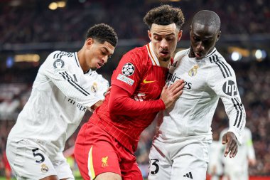 Curtis Jones of Liverpool battles for the ball with Jude Bellingham of Real Madrid and Ferland Mendy during the UEFA Champions League, League Phase MD5 Liverpool v Real Madrid at Anfield, Liverpool, United Kingdom, 27th November 2024 clipart