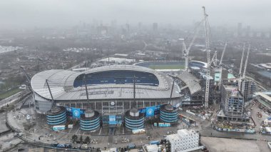 Etihad Stadyumu 'nun hava görüntüsü ve Manchester City, Manchester United ile Etihad Stadyumu' nda oynanan Premier League maçı öncesinde arka planda sisli bir şehir, 15 Aralık 2024
