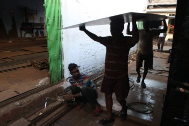 İşçiler 19 Aralık 2024 Perşembe günü Hindistan 'ın Kolkata kentindeki bir çelik ve demir toptancısının önündeki bir kamyona demir levha yüklüyorlar..