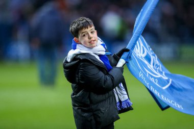 Bir QPR maskotu, 21 Aralık 2024 'te Londra Matrade Loftus Yolu' nda Queens Park Rangers ve Preston North End maçından önce takımların bayrağını sallıyor.