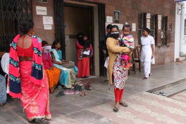 Women with her childs waits on a floor for a rapid antigen test amid Human Metapneumovirus at the emergency ,Hospital in Kolkata, India on January 7, 2025.  clipart