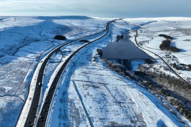 Heavy Snow over the hills of Scammonden Bridge and Booth Wood Reservoir areas of West Yorkshire and a free running M62 where the farm house sits in the middle of the motorway, Kirklees, United Kingdom, 11th January 2025 clipart