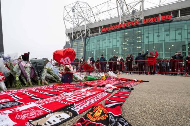 Flowers and scarfs are laid as tribute to the late Dennis Law outside of Old Trafford in front of his statue during the Premier League match Manchester United vs Brighton and Hove Albion at Old Trafford, Manchester, United Kingdom, 19th January 2025 clipart