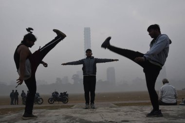 24 Ocak 2025 'te Kolkata' da soğuk bir kış sabahı yoğun sis altında Meydan 'da gençler egzersiz yapıyor. 