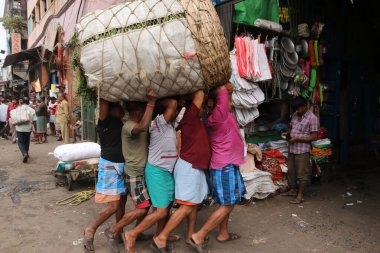 Günlük İşçiler 18 Şubat 2025 'te Hindistan' ın Kolkata kentindeki toptan sebze pazarında bir sepet sebze taşıyorlar.
