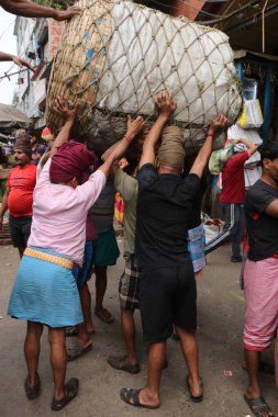 Günlük İşçiler 18 Şubat 2025 'te Hindistan' ın Kolkata kentindeki toptan sebze pazarında bir sepet sebze taşıyorlar.