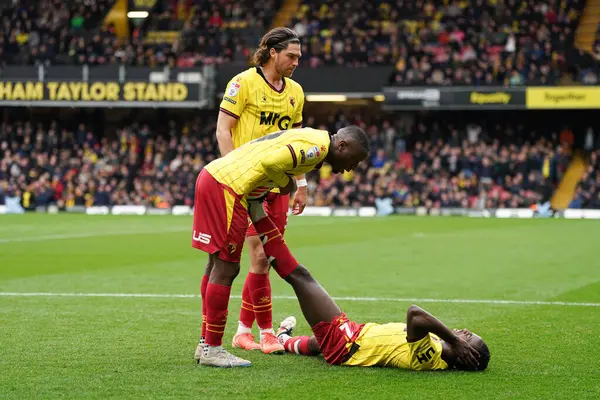 Watford oyuncuları, 23 Şubat 2025 'te İngiltere' nin Watarage Road şehrinde oynanan Gökyüzü İddia Şampiyonası maçında takım arkadaşına krampla yardım ediyor.