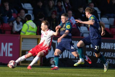 Stevenage 'den Dan Kemp, 1 Mart 2025' te Lamex Stevenage, İngiltere 'de oynanan Sky Bet 1 karşılaşmasında Huddersfield Town' a karşı Joe Hodge 'un baskısıyla ileri pas atıyor.