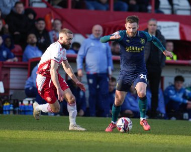 Huddersfield Town takımından Oliver Turton, Stevenage - Huddersfield Town maçında Stevenage - Lamex Stevenage, İngiltere 1 Mart 2025 'te Stevenage' den Dan Butler 'ın baskısı altında topa vuruyor.