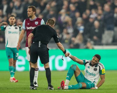 Hakem Michael Salisbury, 10 Mart 2025 'te Londra Stadyumu' nda oynanan Premier League maçı sırasında Newcastle United 'dan Joelinton' a yardım ediyor.