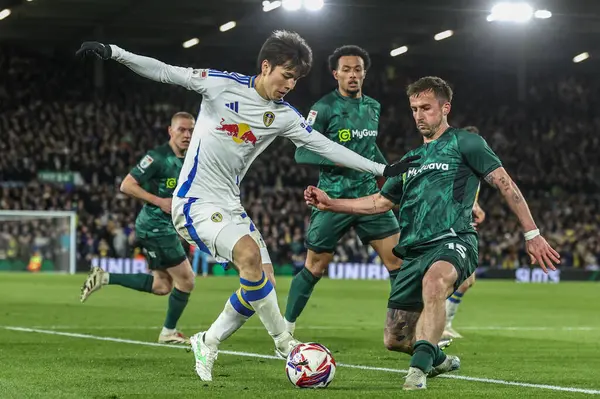 Leeds United 'dan Ao Tanaka ve Millwall' dan Joe Bryan, 12 Mart 2025 'te Leeds Road, Leeds, İngiltere' de oynanan Sky Bet Şampiyonası karşılaşmasında top için mücadele ettiler.