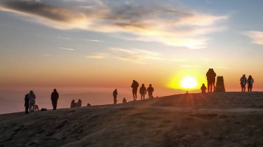 İnsanlar güneşin doğuşunu izlemek için Mam Tor 'un zirvesine gidiyorlar. 19 Mart 2025' te Mam Tor, Peak District, Birleşik Krallık 'taki Hope Vadisi' nin üzerinde bir sis örtüsü olarak duruyorlar.
