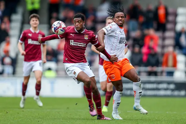 Northampton Town 'dan Tyler Magloire, 21 Mart 2025 tarihinde Northampton Town' a karşı Blackpool 'da oynanan Sky Bet 1 karşılaşmasında Blackpool' lu Niall Ennis ile top için mücadele etti.