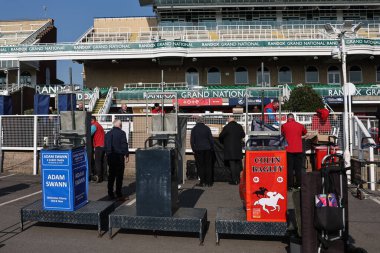 Bahisçiler, 3 Nisan 2025 'te Aintree Yarış Pisti, Liverpool' da düzenlenen Randox Grand National 2025 1. Açılış Günü 'nde tribünlerini yarışa hazırlıyorlar.