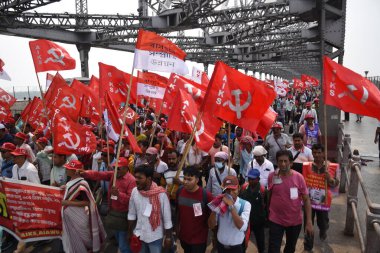 Parti bayraklarıyla solcu aktivistler 20 Nisan 2025 'te Kolkata' daki toplu toplantıya katılmak için Ganga nehri üzerindeki köprüden geçiyorlar. 2026 parlamento seçimleri yaklaşırken, CPI (M) Genel Sekreteri Mohammad Salim
