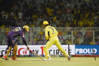 Chennai Süper Kralları 'nın kaptanı Mahendra Singh Dhoni, sağda, Kolkata Şövalyeleri' nden Sunil Narine 'i kovmak için gereken engelleri aşıyor. Kolkata Şövalyeleri ve Chennai Süper Kralları arasında oynanan 2025 IPL maçı sırasında, 7 Mayıs 2025 tarihinde, Kolka Bahçeleri' nde,