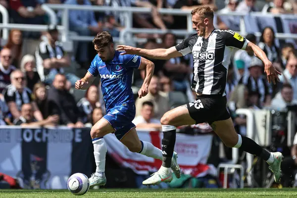 Chelsea 'den Pedro Neto, Newcastle United takımının 11 Mayıs 2025' te St. James 's Park, Newcastle' da oynanan Premier League karşılaşmasında Dan Burn 'ün izlediği topla topu bırakıyor.