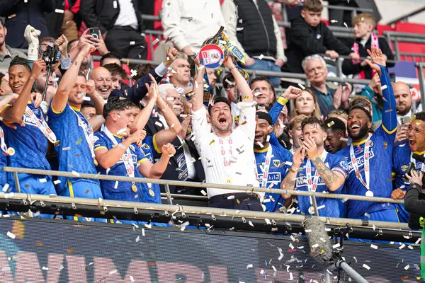 AFC Wimbledon teknik direktörü Johnnie Jackson, 26 Mayıs 2025 'te Wembley Stadyumu, Londra' da oynanan Wimbledon-Walsall maçında Sky Bet 2 playoff final maçında kupayla kutluyor.