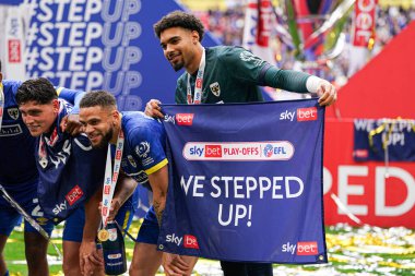 AFC Wimbledon 'dan Owen Goodman, 26 Mayıs 2025' te Wembley Stadyumu 'nda Wimbledon ile Walsall arasındaki Sky Bet 2 playoff final maçında terfiden sonra pankartı yükseltti.