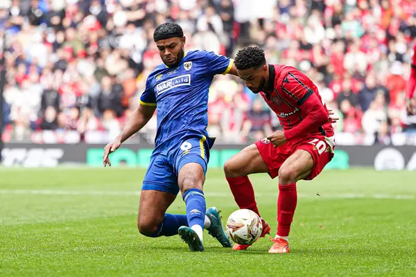 AFC Wimbledon takımından Ryan Johnson, 26 Mayıs 2025 'te Wembley Stadyumu, Londra' da oynanan Wimbledon-Walsall maçında George Hall of Walsall 'dan top kazanmaya çalıştı.